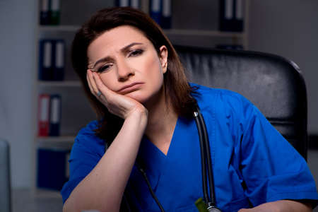 Aged female doctor working at night shiftの写真素材