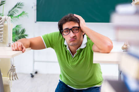 Funny male student in the classroom with skeletonの写真素材