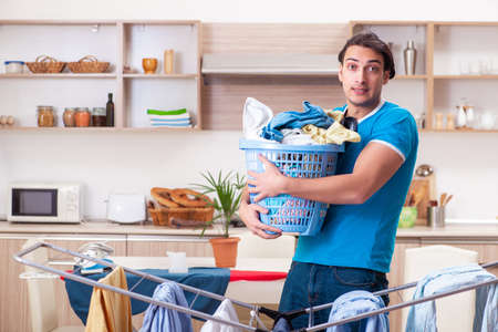 Young man husband doing clothing ironing at homeの写真素材