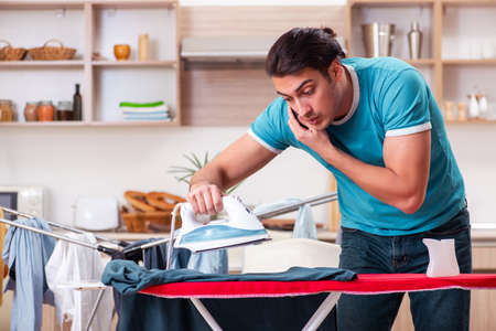 Young man husband doing clothing ironing at homeの写真素材