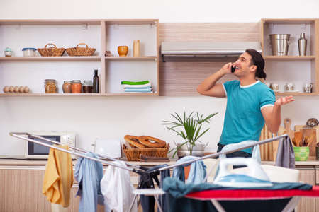 Young man husband doing clothing ironing at homeの写真素材