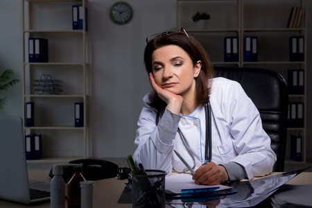 Aged female doctor working at night shiftの写真素材