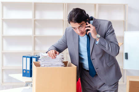 Young man employee with boxes in the officeの写真素材