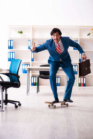 Young handsome businessman with longboard in the officeの写真素材