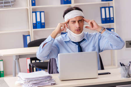 Young injured male employee working in the officeの写真素材