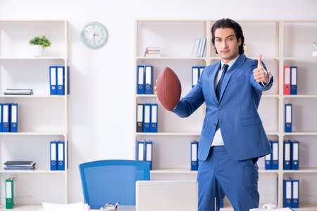 Young handsome businessman with rugby ball in the officeの写真素材