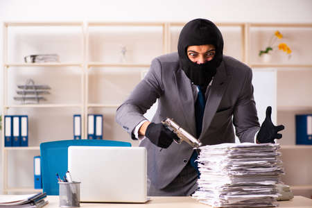 Male gangster stealing information from the officeの写真素材