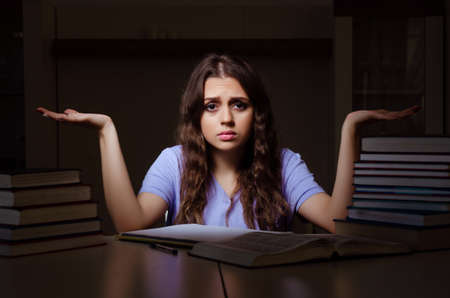 Young female student preparing for exams late at homeの写真素材