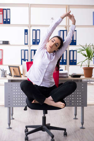 Young female employee doing exercises in the officeの写真素材