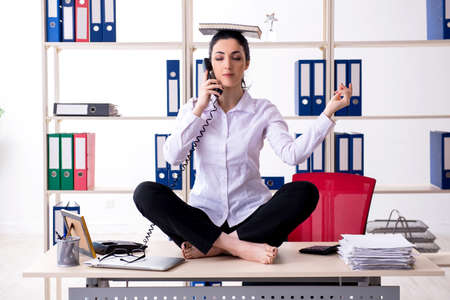 Young female employee doing exercises in the officeの写真素材