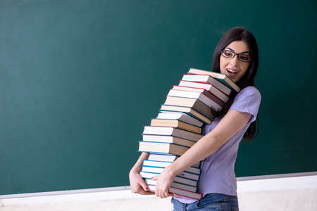 Young female teacher student in front of green boardの写真素材