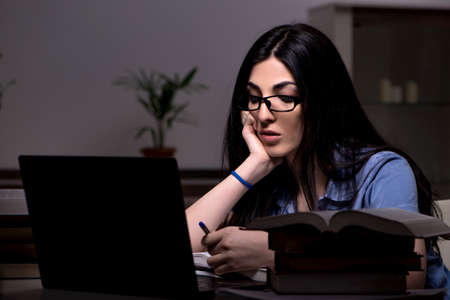 Young female student preparing for exams at night timeの写真素材