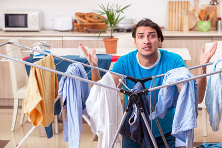 Young man husband doing clothing ironing at homeの写真素材