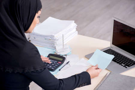 Female employee bookkeeper in hijab working in the office