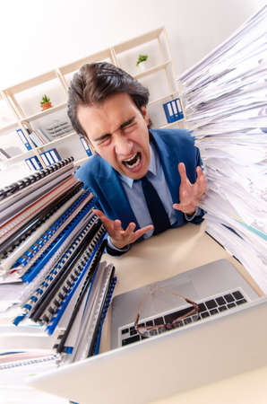 Young handsome businessman unhappy with excessive workの写真素材