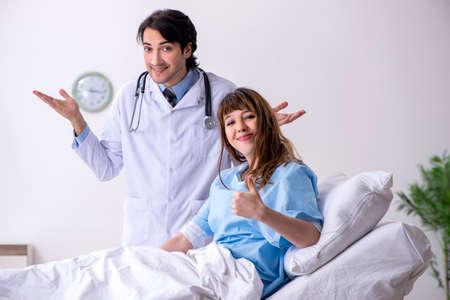 Male doctor visiting female patient in wardの写真素材