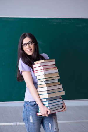 Young female teacher student in front of green boardの写真素材
