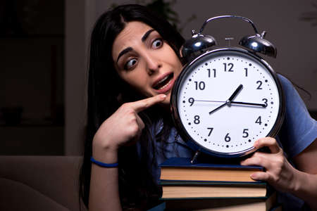 Young female student preparing for exams at night timeの写真素材