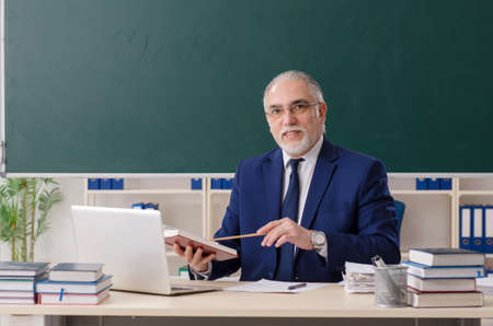 Aged male teacher in front of chalkboardの写真素材