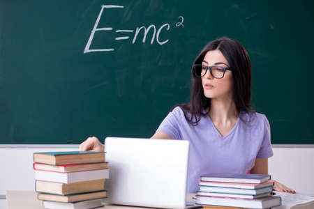 Young female teacher student in front of green board