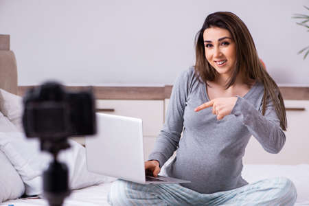 Pregnant woman recording video for her blog