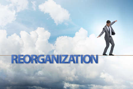 Reorganisation concept with businessman walking on tight ropeの写真素材