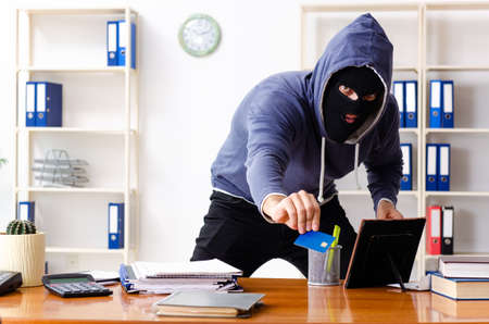 Male thief in balaclava in the officeの写真素材