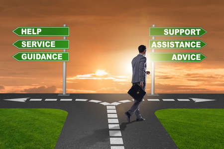 Businessman having hard choice standing at crossroadsの写真素材