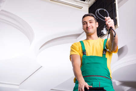 Young repairman repairing ceiling air conditioning unitの写真素材