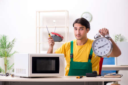 Young repairman repairing microwave in service centreの写真素材