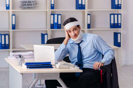 Young injured male employee working in the officeの写真素材