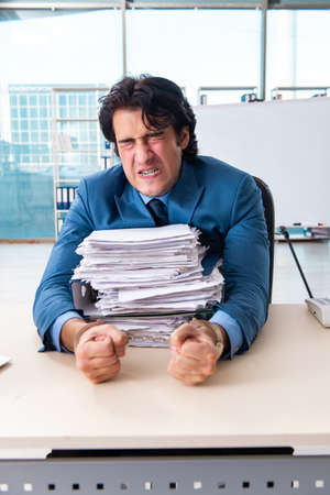 Chained male employee unhappy with excessive workの写真素材