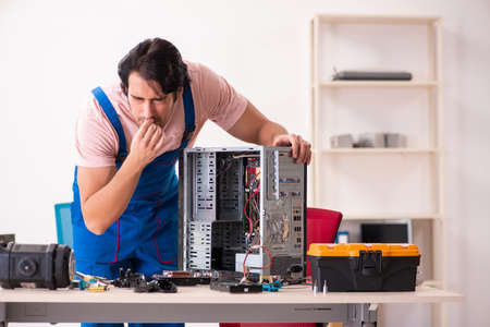 Young male contractor repairing computer