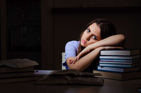 Young female student preparing for exams late at homeの写真素材