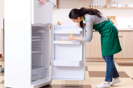 Young woman cleaning fridge in hygiene conceptの写真素材