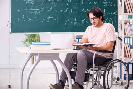 Young handsome man in wheelchair in front of chalkboard