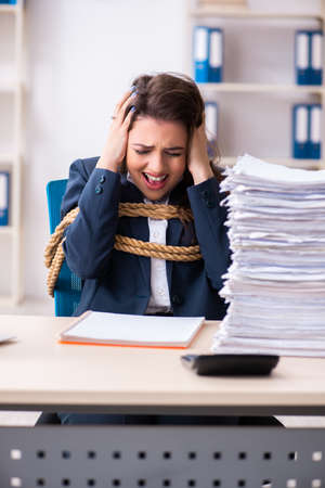 Young beautiful employee tied up with rope in the officeの写真素材