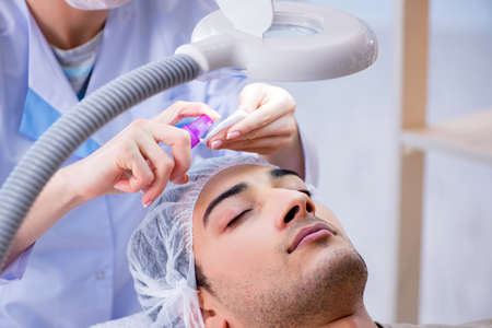 Young handsome man visiting female doctor cosmetologistの写真素材