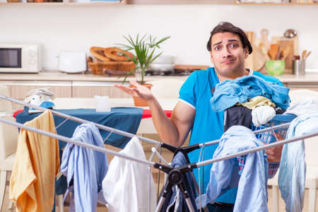 Young man husband doing clothing ironing at homeの写真素材