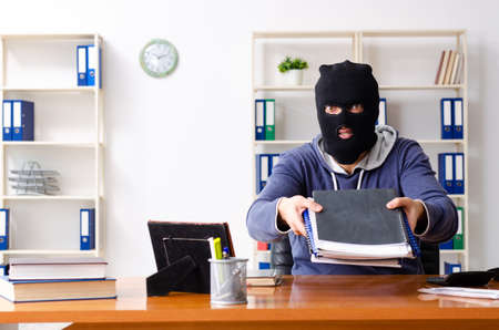 Male thief in balaclava in the officeの写真素材