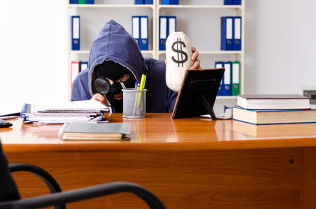 Male thief in balaclava in the officeの写真素材