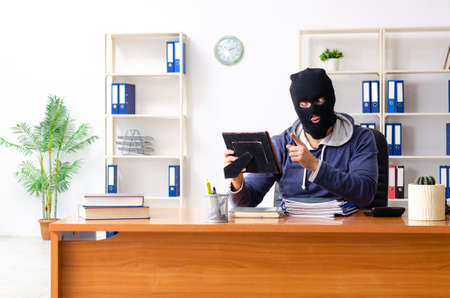 Male thief in balaclava in the officeの写真素材