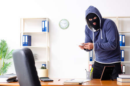 Male thief in balaclava in the officeの写真素材