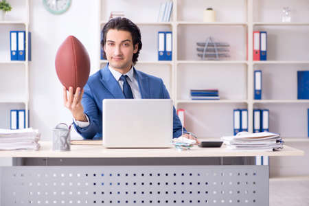 Young handsome businessman with rugby ball in the officeの写真素材