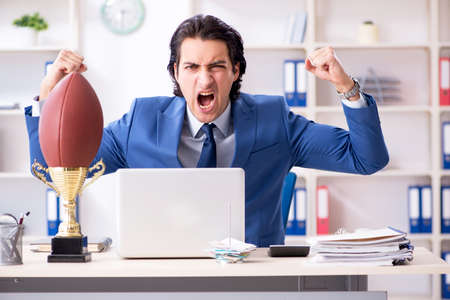 Young handsome businessman with rugby ball in the officeの写真素材
