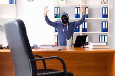 Male thief in balaclava in the officeの写真素材