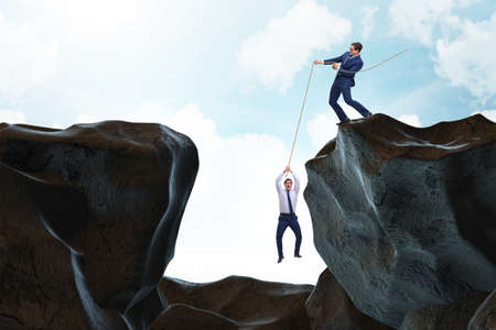 Businessman helping colleague with ropeの写真素材