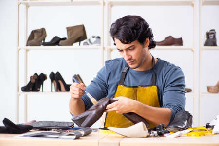 Young man repairing shoes in workshopの写真素材