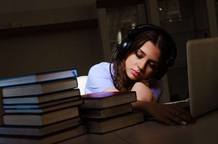 Young female student preparing for exams late at homeの写真素材