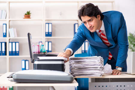 Young employee making copies at copying machine